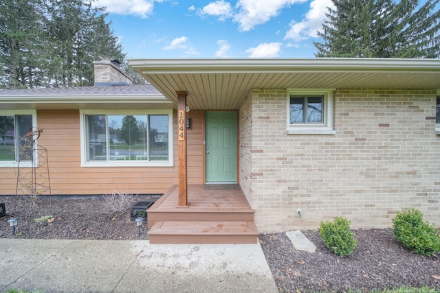 property entrance with a chimney and brick siding