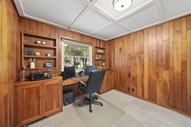 carpeted office space featuring wooden walls, visible vents, built in shelves, and coffered ceiling