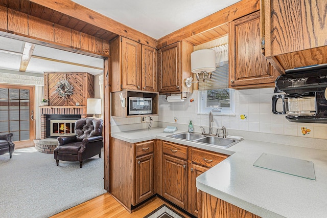 kitchen with light countertops, decorative backsplash, brown cabinetry, and a sink