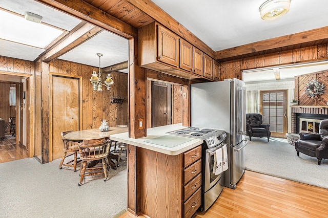 kitchen with a fireplace, wooden walls, light countertops, brown cabinets, and appliances with stainless steel finishes