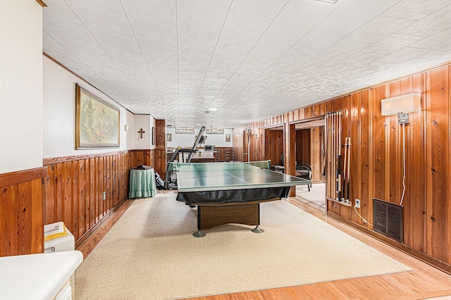 game room featuring a wainscoted wall, wood walls, wood finished floors, and visible vents
