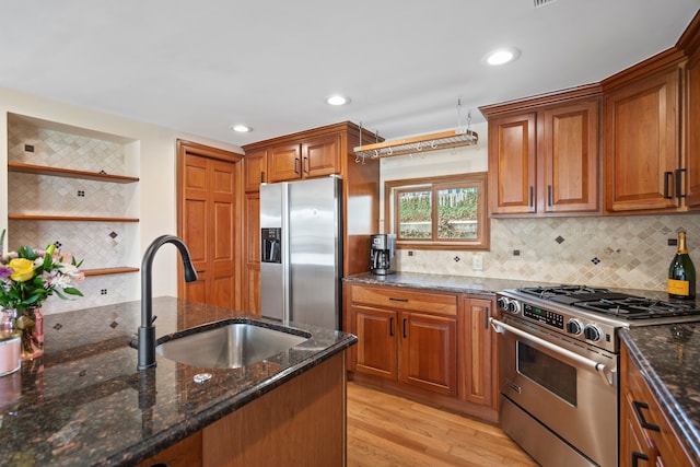 kitchen with brown cabinets, open shelves, a sink, light wood-style floors, and appliances with stainless steel finishes