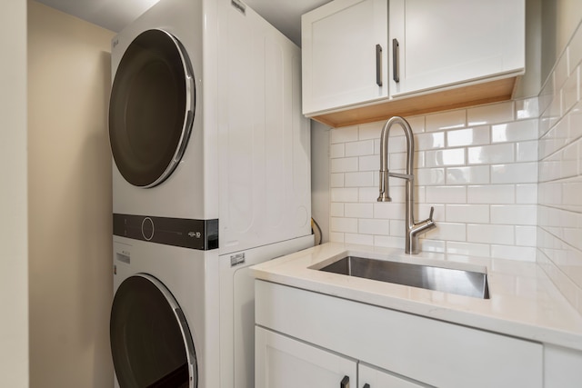 laundry room featuring cabinet space, stacked washer and dryer, and a sink