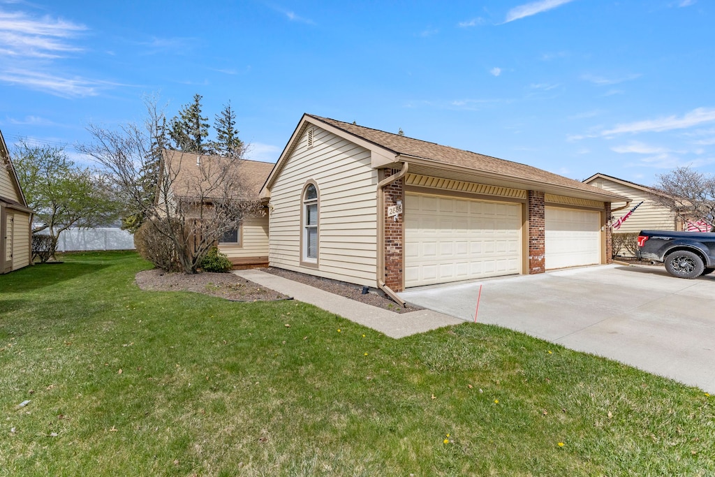 view of side of property with brick siding, a lawn, concrete driveway, and roof with shingles