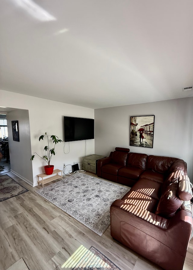living room with baseboards, visible vents, and wood finished floors