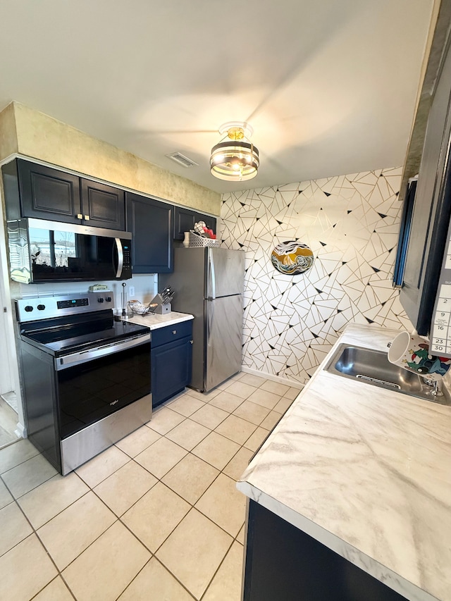 kitchen featuring light countertops, a sink, appliances with stainless steel finishes, and light tile patterned floors