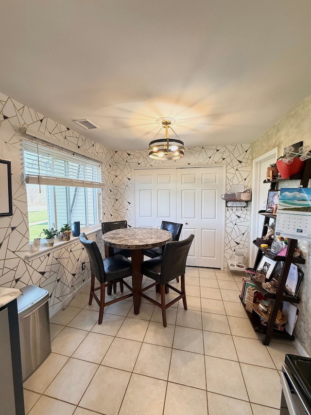 dining room with light tile patterned flooring, wallpapered walls, visible vents, and a chandelier