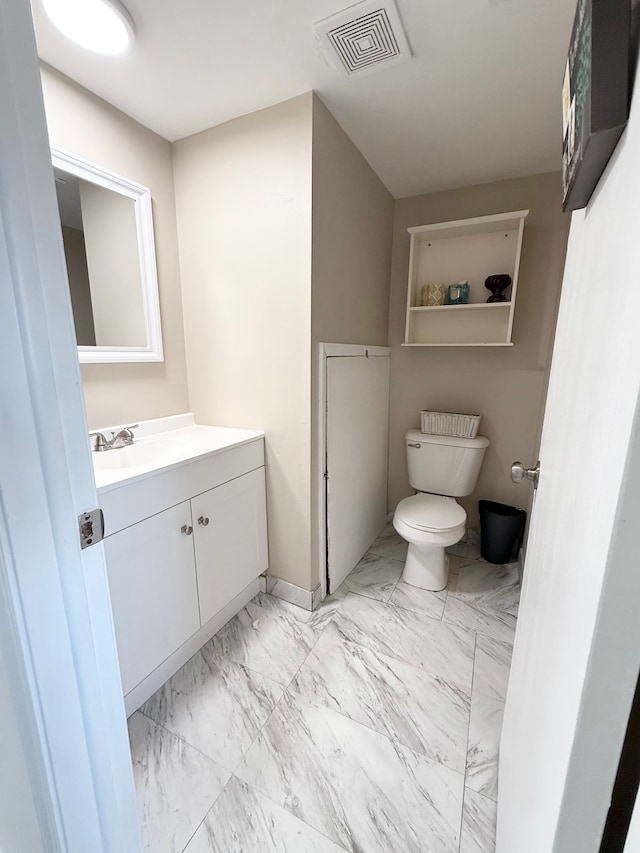 half bath featuring vanity, toilet, marble finish floor, and visible vents