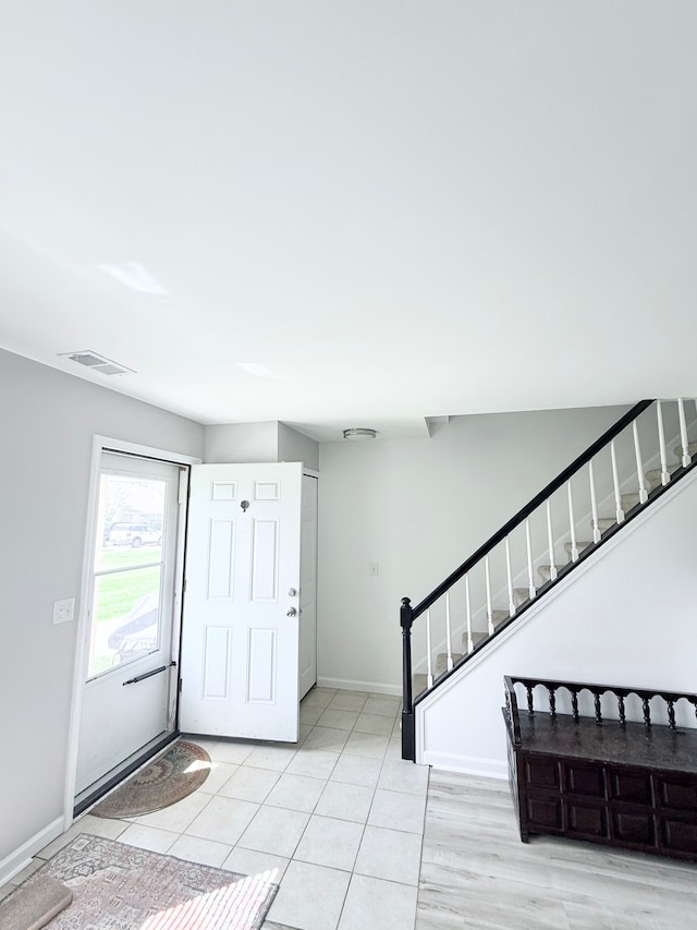 foyer with stairway, baseboards, light tile patterned floors, and visible vents