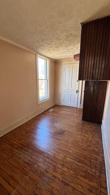 unfurnished room featuring wood finished floors, crown molding, and baseboards