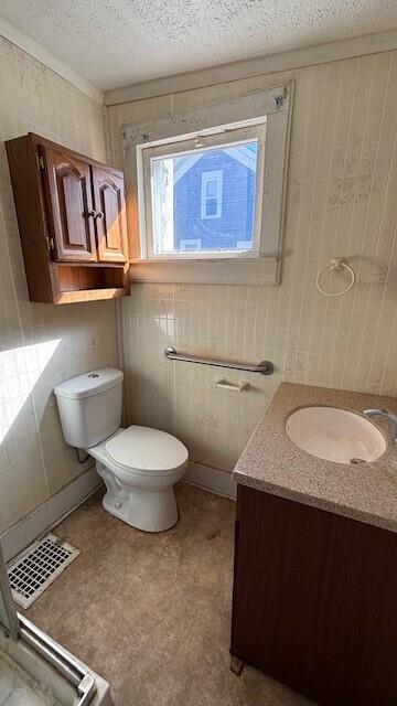 bathroom with toilet, vanity, a textured ceiling, and visible vents