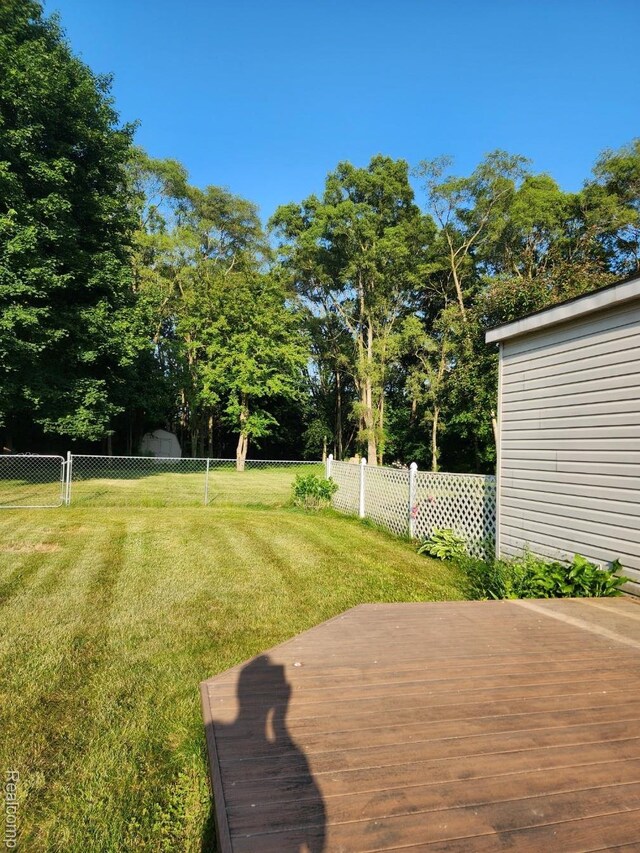 5140 Eastview Rd, Clarkston, MI 48346 - fenced backyard featuring a wooden deck and a storage unit
