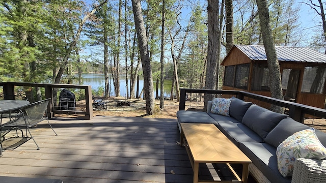 wooden deck with outdoor dining area, an outdoor living space, and a water view
