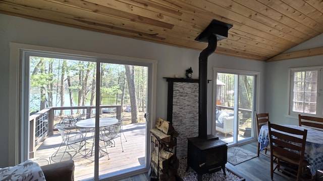 dining room with lofted ceiling, wooden ceiling, wood finished floors, and a wood stove