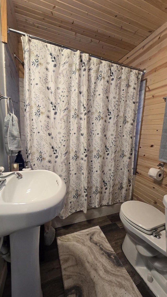 bathroom with a shower with shower curtain, wood walls, wood ceiling, and toilet