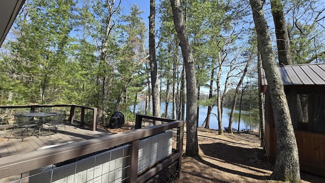 deck with a water view and outdoor dining space