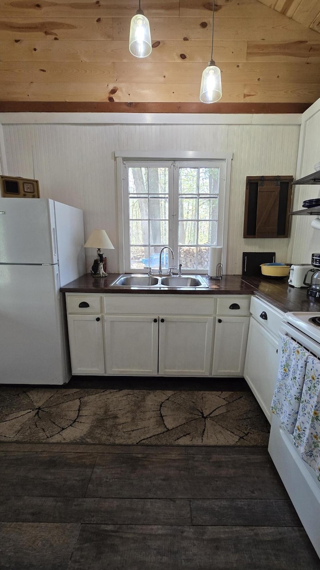 kitchen featuring dark countertops, a sink, white appliances, white cabinets, and dark wood-style flooring