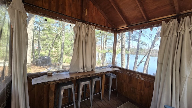 unfurnished sunroom with vaulted ceiling, a water view, wood ceiling, and wood finished floors