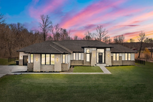 view of front of home featuring a shingled roof, a front lawn, an attached garage, driveway, and brick siding