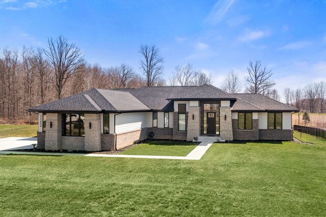 view of front of house with fence, brick siding, a front yard, and roof with shingles