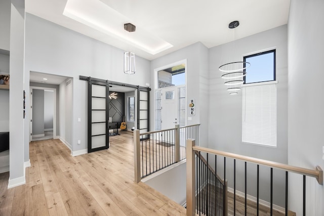 hall featuring a barn door, baseboards, wood finished floors, and a high ceiling