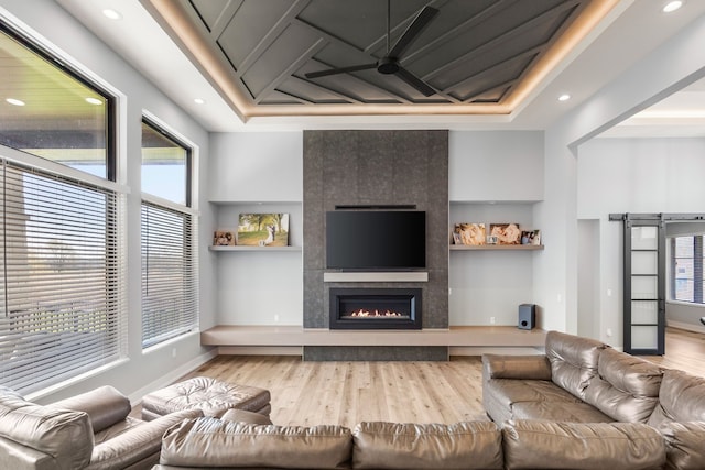 living room featuring light wood finished floors, a tiled fireplace, recessed lighting, and a ceiling fan