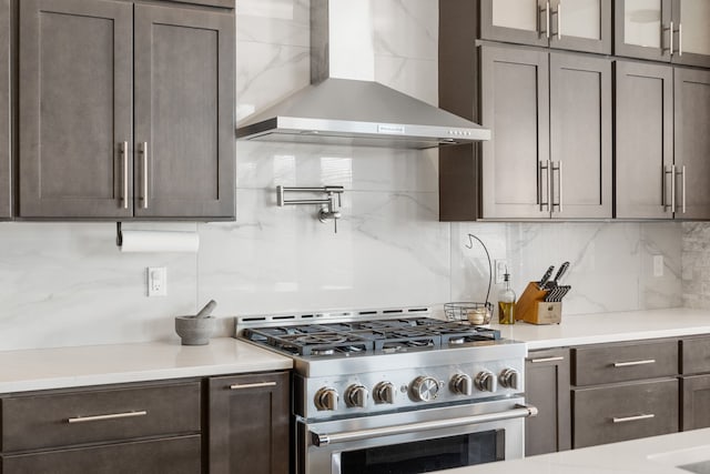 73404 Castle, Armada, MI 48005 - kitchen featuring high end stove, wall chimney range hood, decorative backsplash, light countertops, and dark brown cabinets