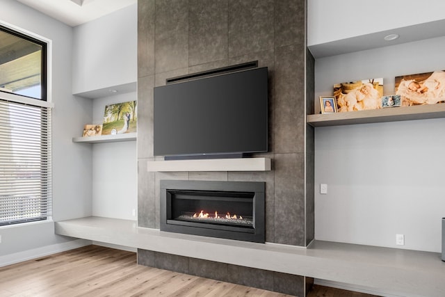 unfurnished living room with baseboards, wood finished floors, and a large fireplace