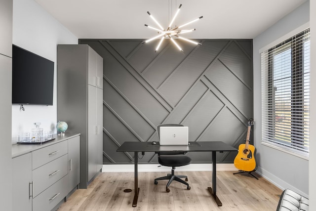 home office with light wood-style floors, a decorative wall, baseboards, and a notable chandelier