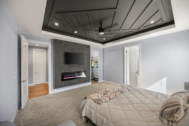 bedroom with a tray ceiling, a spacious closet, light colored carpet, and recessed lighting