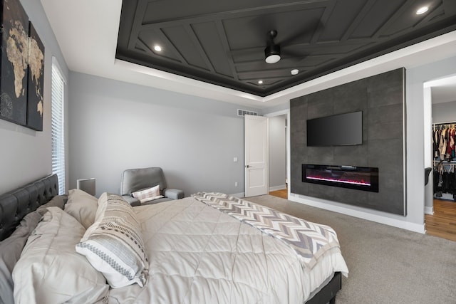 carpeted bedroom featuring baseboards, visible vents, a spacious closet, recessed lighting, and a tile fireplace