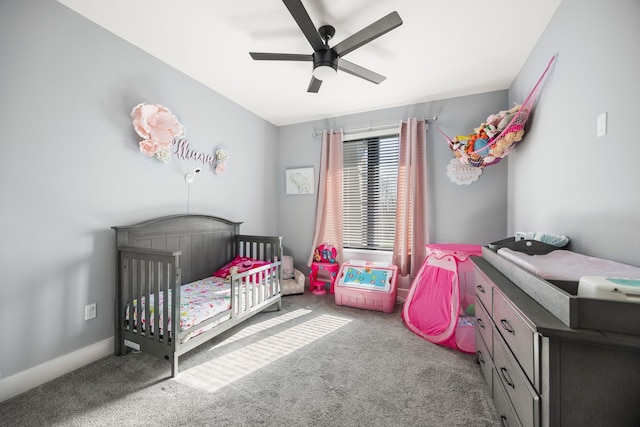 bedroom featuring a nursery area, carpet flooring, and a ceiling fan