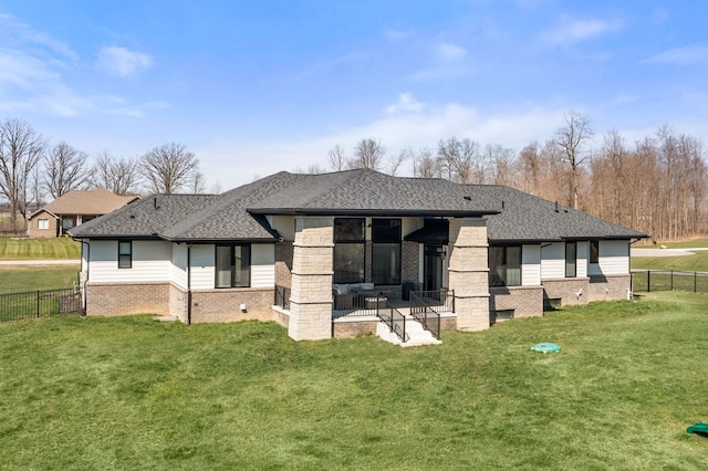 rear view of property featuring a fenced backyard, brick siding, and roof with shingles