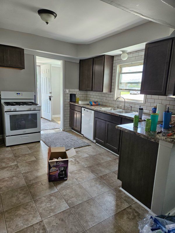 22419 Hoffman St, Saint Clair Shores, MI 48082 - kitchen with decorative backsplash, light stone countertops, dark brown cabinets, a sink, and white appliances