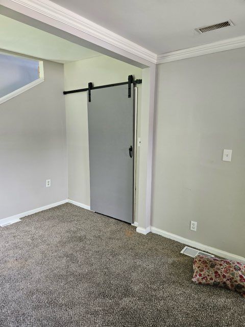 22419 Hoffman St, Saint Clair Shores, MI 48082 - carpeted empty room featuring crown molding, baseboards, visible vents, and a barn door