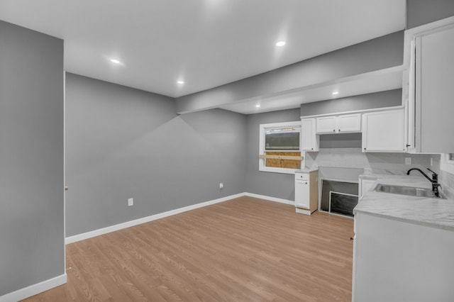 kitchen featuring recessed lighting, light wood finished floors, white cabinetry, and a sink
