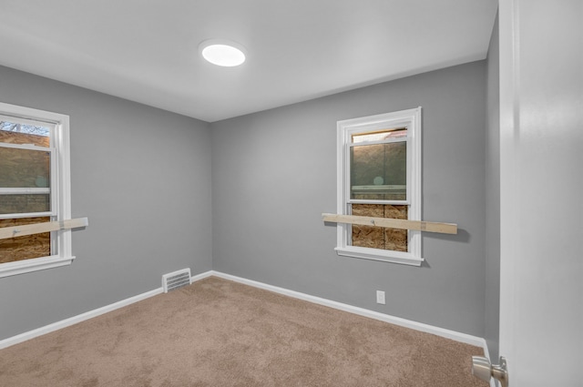carpeted spare room with plenty of natural light, baseboards, and visible vents