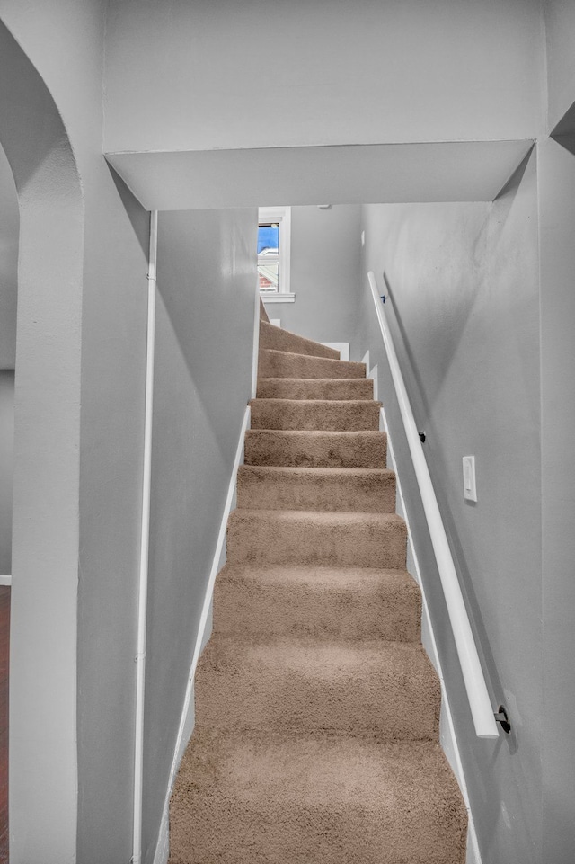staircase with baseboards and arched walkways