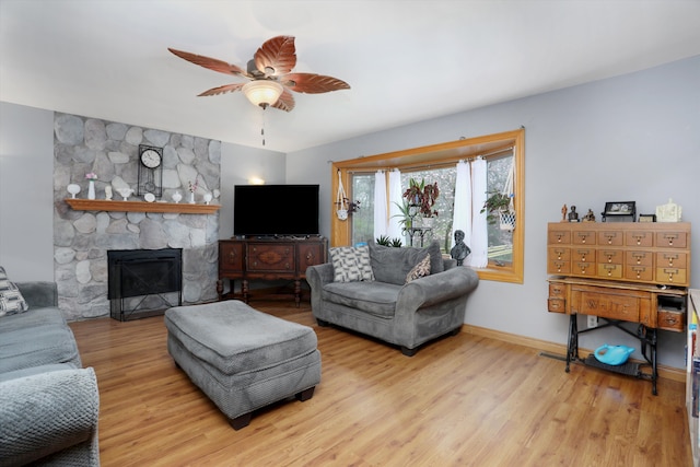 826 Hendricks Dr, Monroe, MI 48162 - living room featuring a stone fireplace, baseboards, a ceiling fan, and wood finished floors