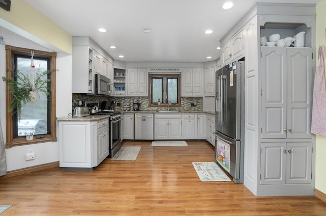 826 Hendricks Dr, Monroe, MI 48162 - kitchen with a sink, decorative backsplash, light wood-style floors, stainless steel appliances, and white cabinetry