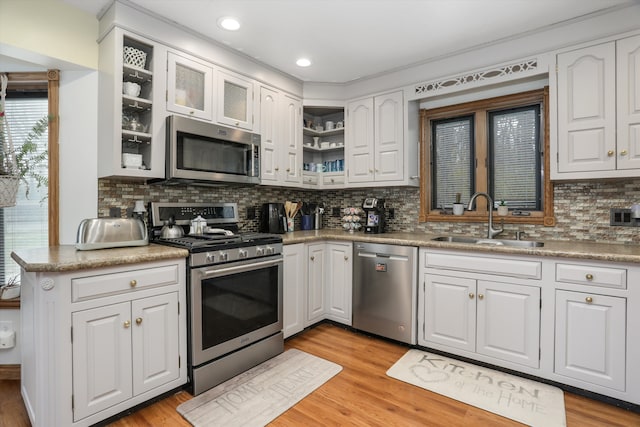826 Hendricks Dr, Monroe, MI 48162 - kitchen featuring light wood finished floors, a sink, white cabinetry, decorative backsplash, and appliances with stainless steel finishes