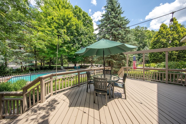 wooden deck with a fenced in pool and outdoor dining space