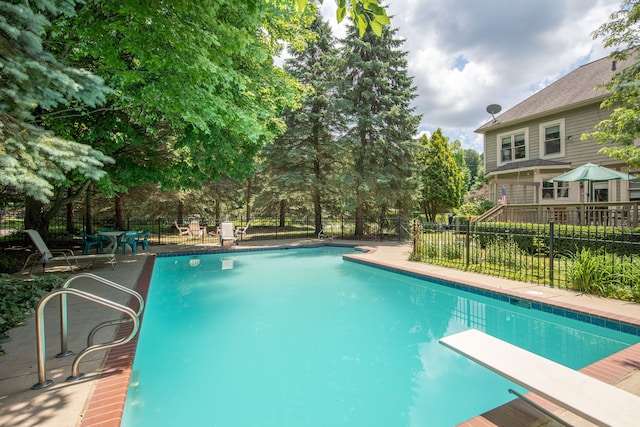 view of swimming pool featuring fence, a fenced in pool, and a diving board