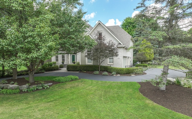 view of front facade featuring brick siding, driveway, and a front lawn