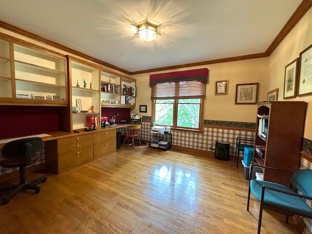 home office with built in desk, light wood-style floors, a wainscoted wall, and crown molding
