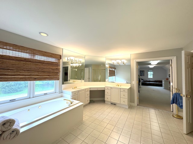 ensuite bathroom featuring tile patterned flooring, vanity, connected bathroom, a garden tub, and a notable chandelier