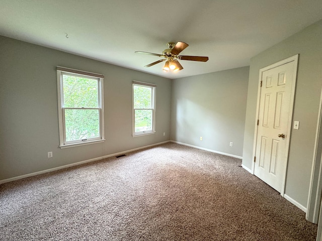 carpeted spare room featuring ceiling fan, baseboards, and visible vents