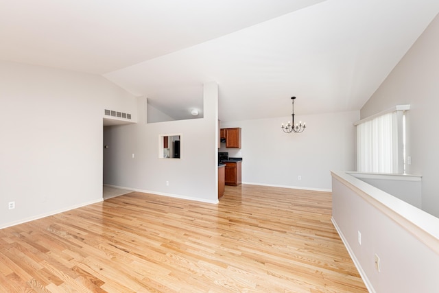unfurnished living room featuring vaulted ceiling, light wood finished floors, visible vents, and an inviting chandelier