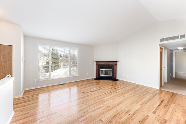 unfurnished living room featuring light wood-type flooring, visible vents, and a fireplace with flush hearth