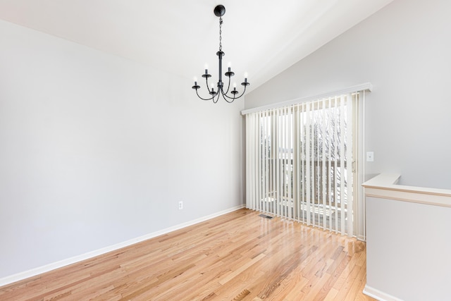 unfurnished room featuring vaulted ceiling, wood finished floors, an inviting chandelier, baseboards, and visible vents